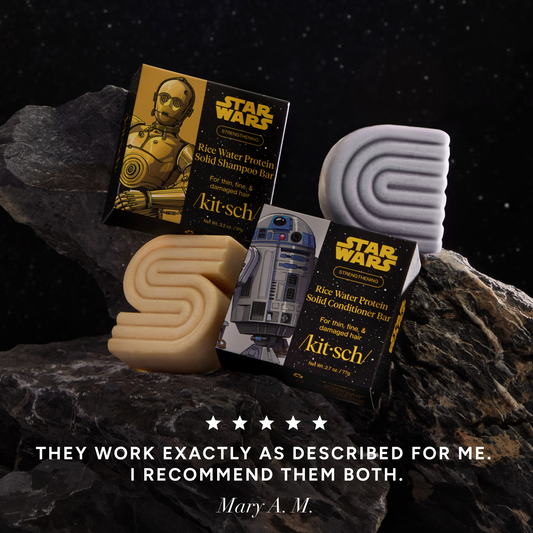 5-star customer review creative product shoot for KITSCH x Star Wars™ Solid Shampoo & Conditioner Combo on dark space-themed rocky background — C-3PO shampoo bar, R2-D2 conditioner bar, and both Star Wars gift boxes styled on rocks with galaxy backdrop — Mary M.: "THEY WORK EXACTLY AS DESCRIBED FOR ME. I RECOMMEND THEM BOTH."