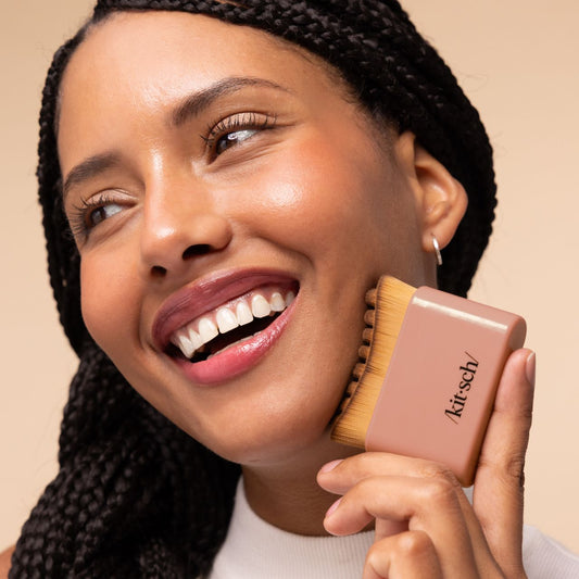 Model using the terracotta Kitsch Lymphatic Contour Face Brush to massage her cheek