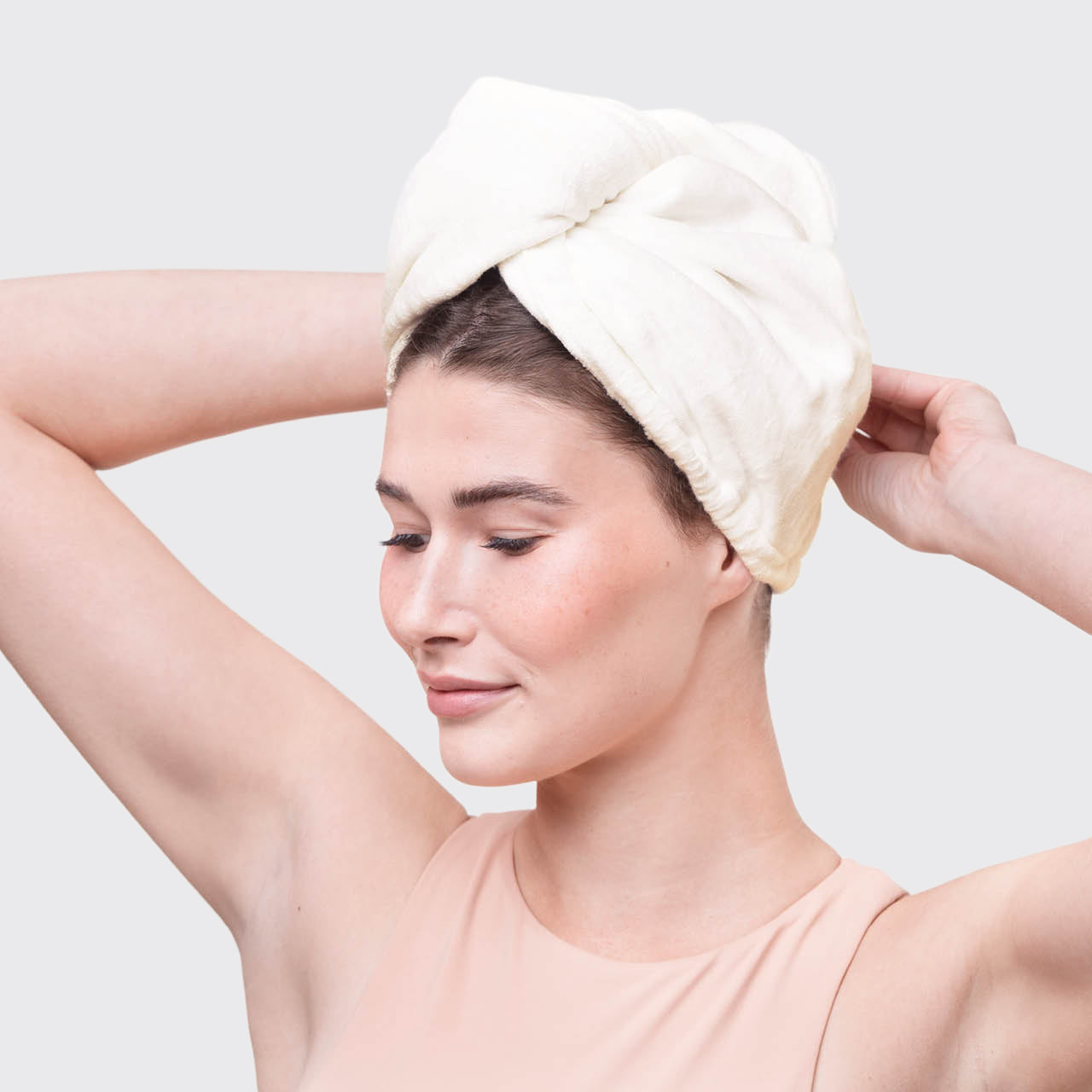 Model wrapping wet hair with a white Organic Bamboo Hair Towel after showering.