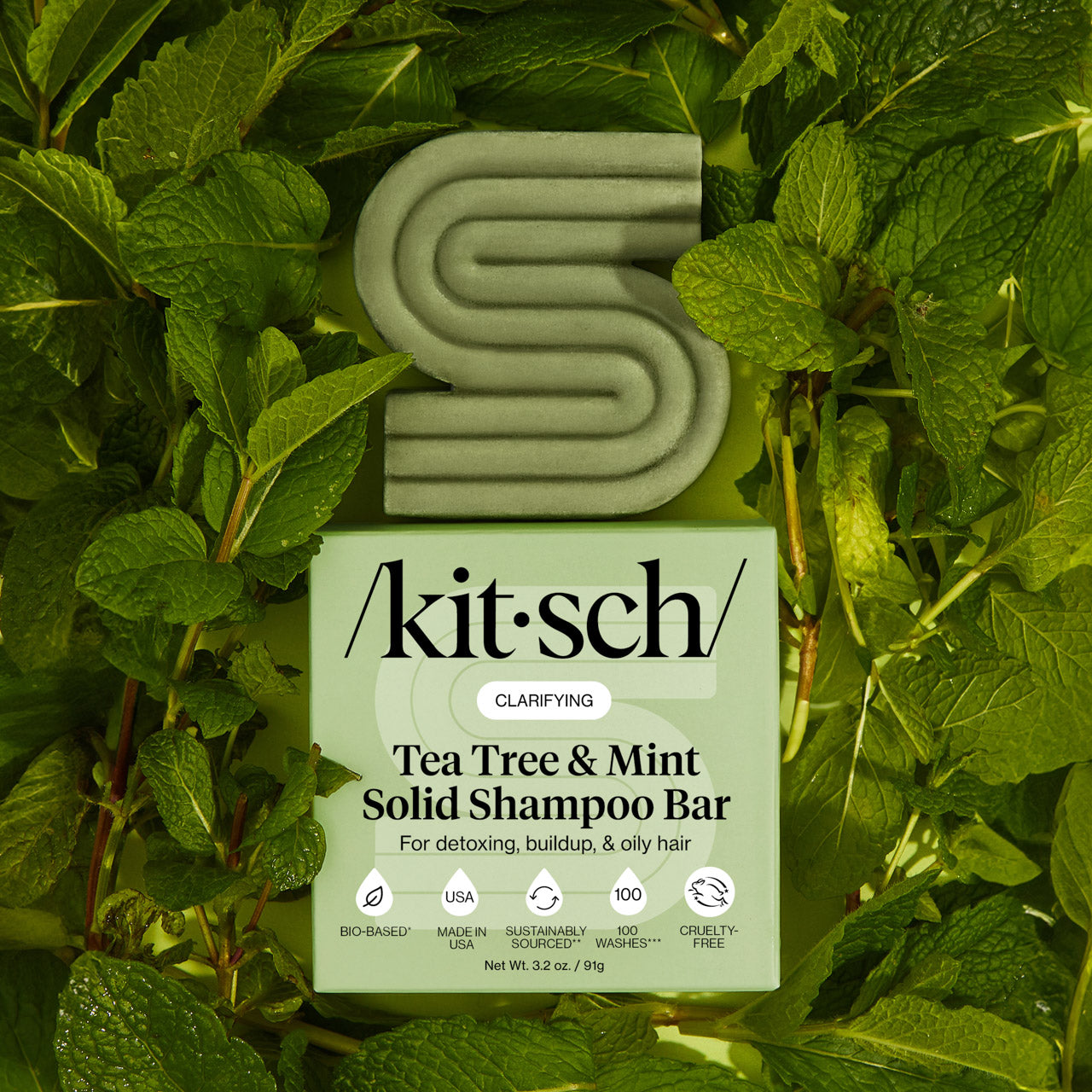 KITSCH Tea Tree & Mint Clarifying Solid Shampoo Bar and packaging box displayed on lush fresh mint leaf background — labeled CLARIFYING, For oiliness, buildup, & oily hair — bottle-free clarifying shampoo bar for oily, buildup-prone hair and scalp