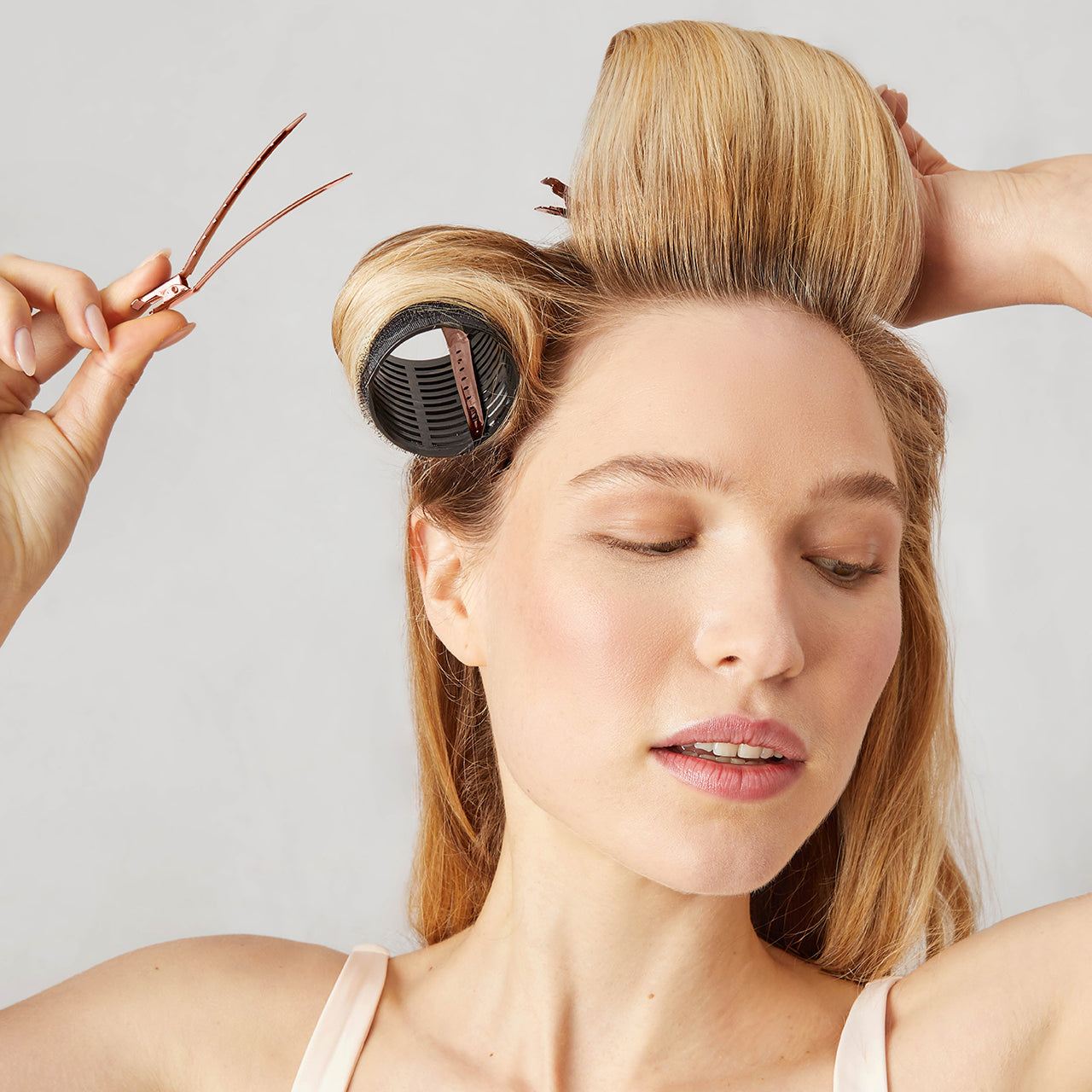 Kitsch Hair Rollers + Styling Clips Bundle lifestyle shot with model in soft pink setting