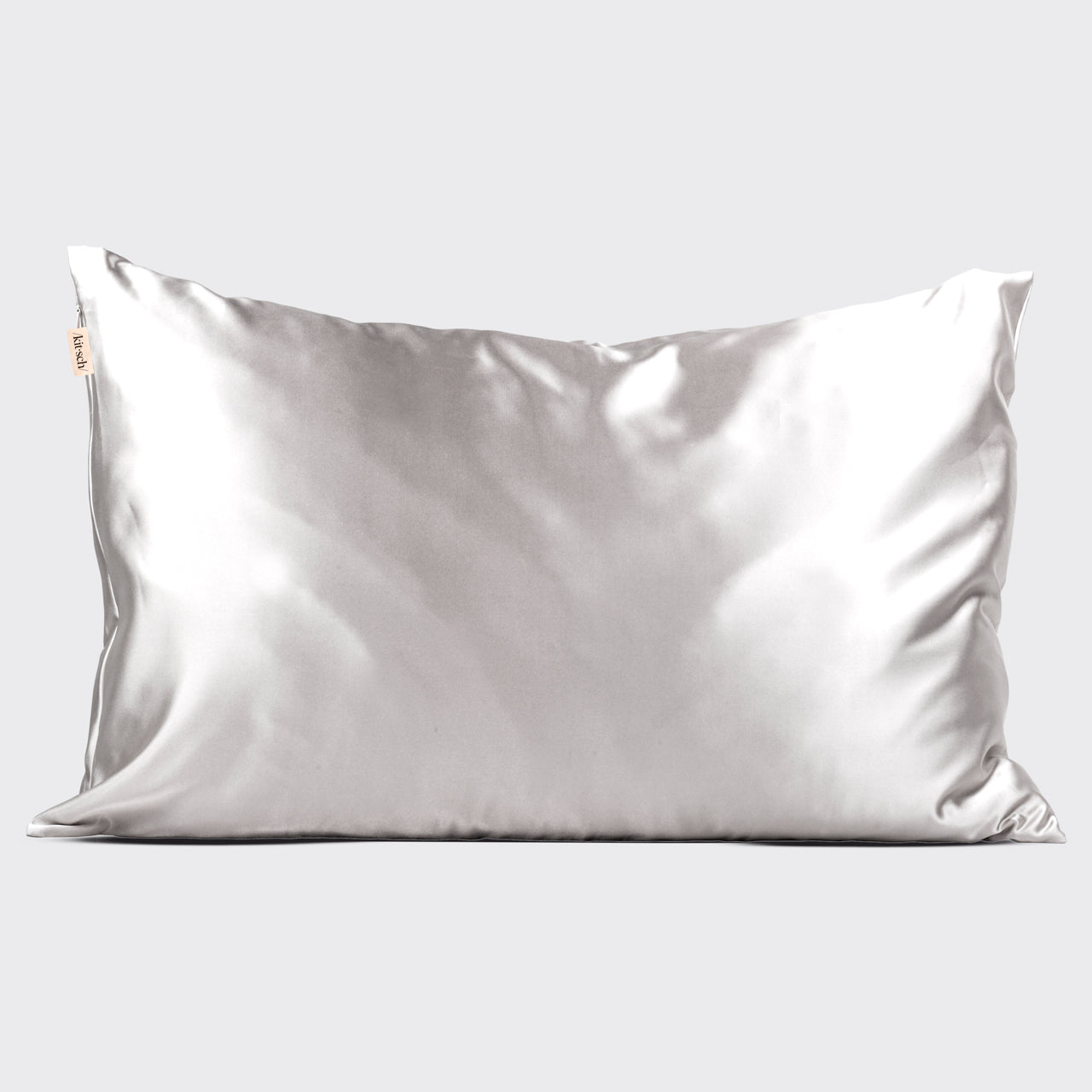 Kitsch Silver Satin Pillowcase styled on a bed with soft light and minimal bedding