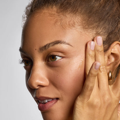 Model applying Hydrating Dermaplane Oil to her face as part of a skincare routine.