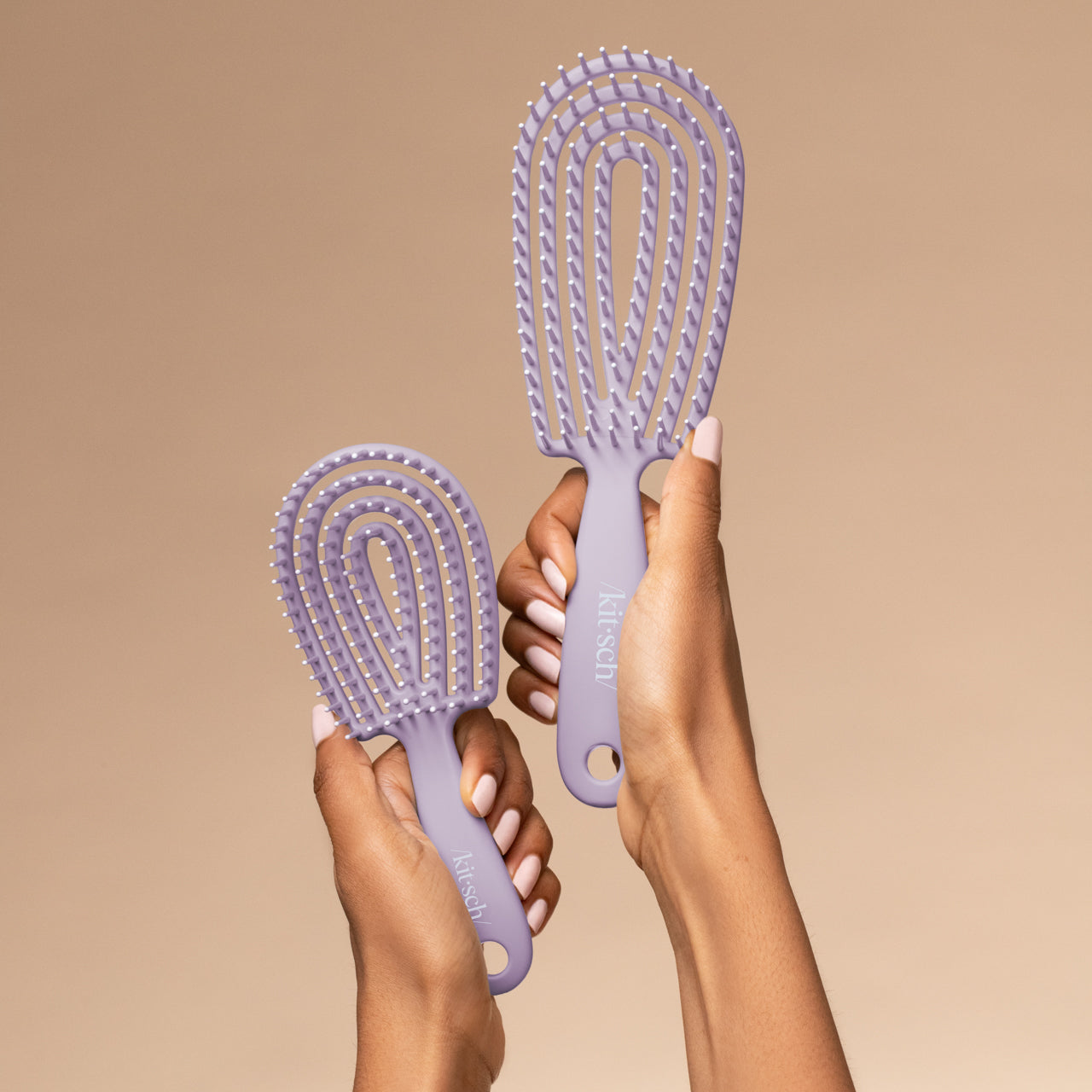 Hand holding the Kitsch Soft Violet Detangling Flexi Brush Mini showing travel-friendly size