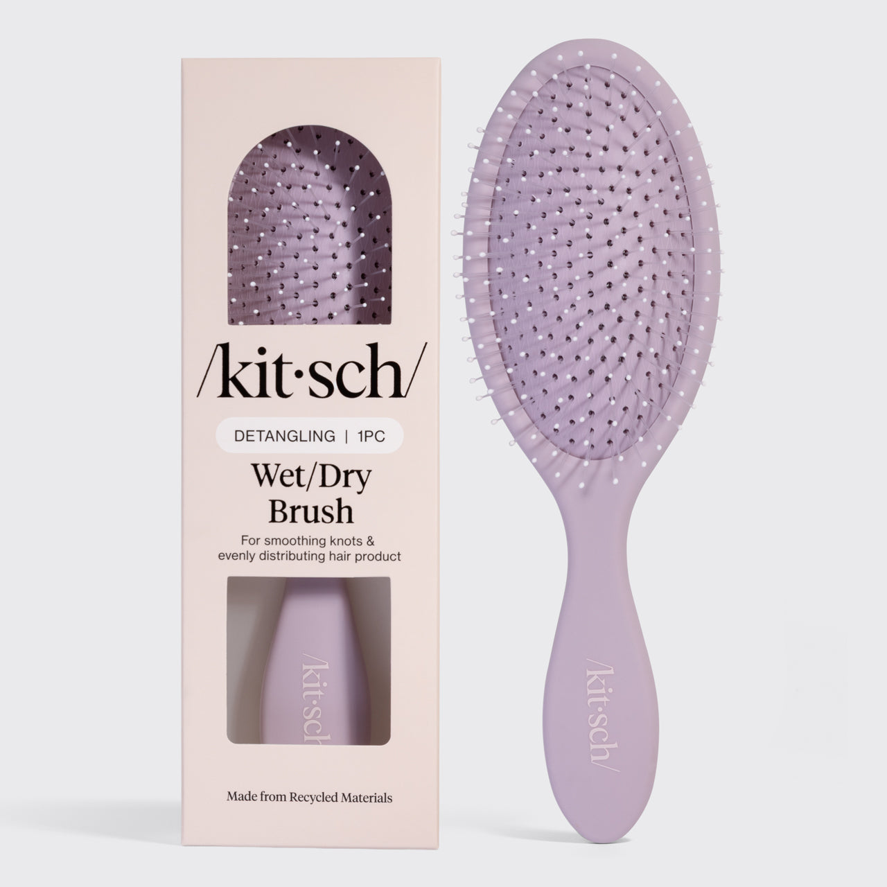 Kitsch Detangling Wet/Dry Brush in lavender, shown next to its blush pink retail packaging. Made from recycled materials, designed for smoothing knots and evenly distributing hair product.
