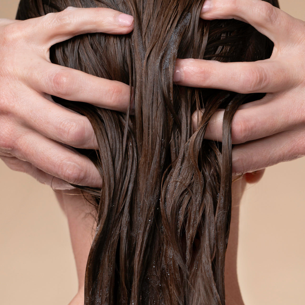 Close-up of hands running through wet hair after applying KITSCH Strengthening Rice Water Protein Conditioner