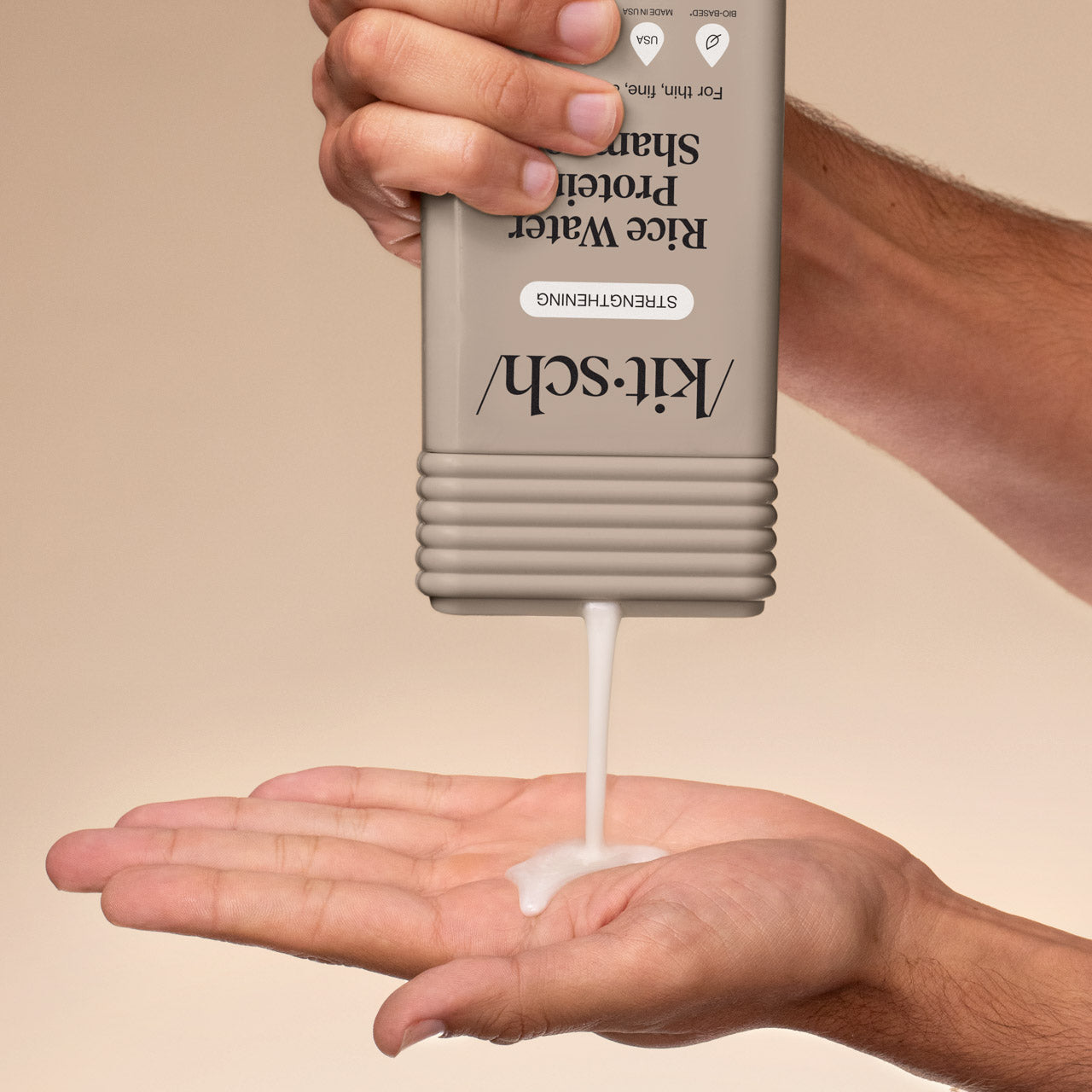 Hand dispensing KITSCH Rice Water Protein Strengthening Shampoo from bottle into palm on a beige background