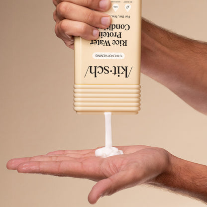 Hand dispensing KITSCH Rice Water Protein Strengthening Conditioner from bottle into palm on a beige background