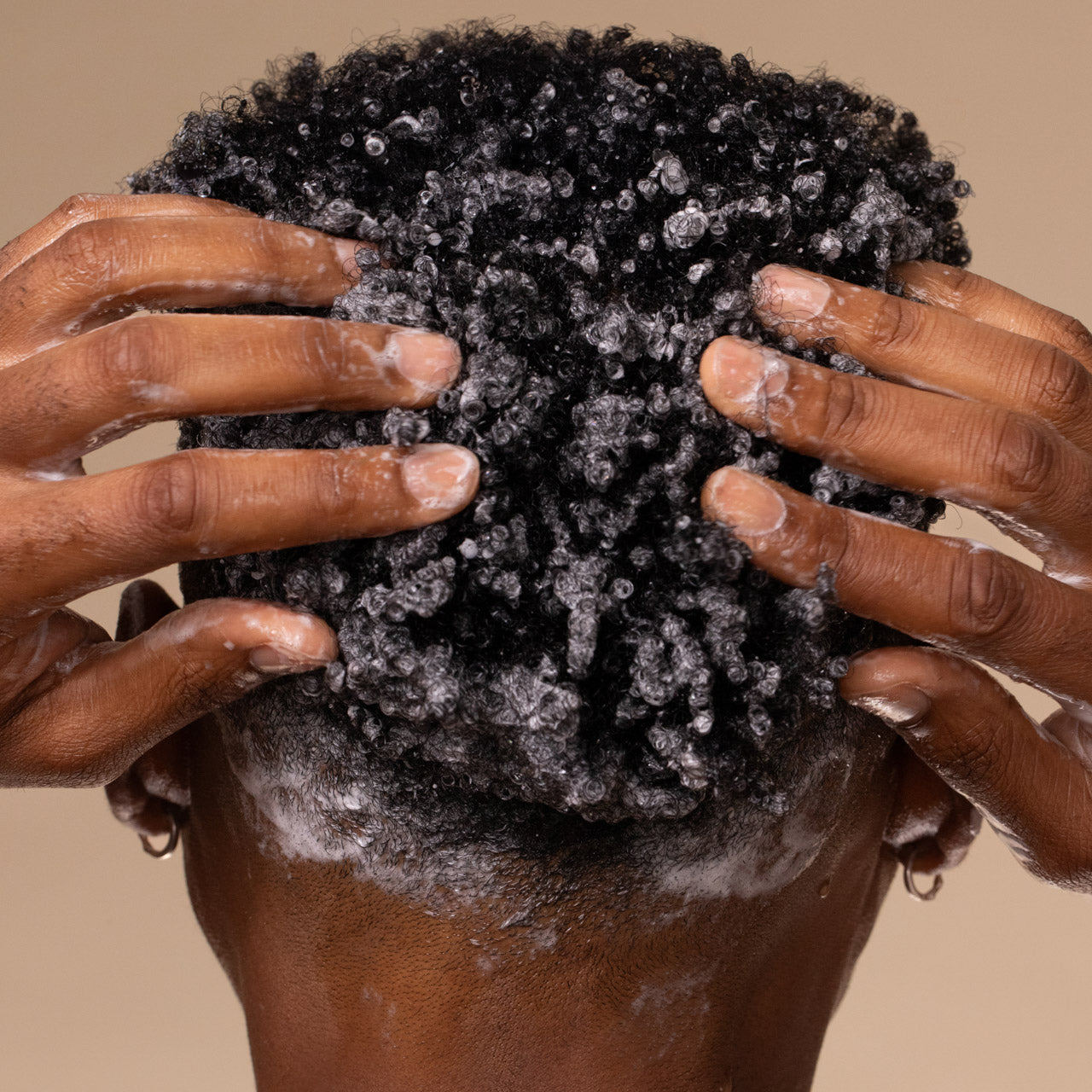 Person massaging KITSCH Coconut Oil Shampoo lather into kinky coily hair, demonstrating how to use