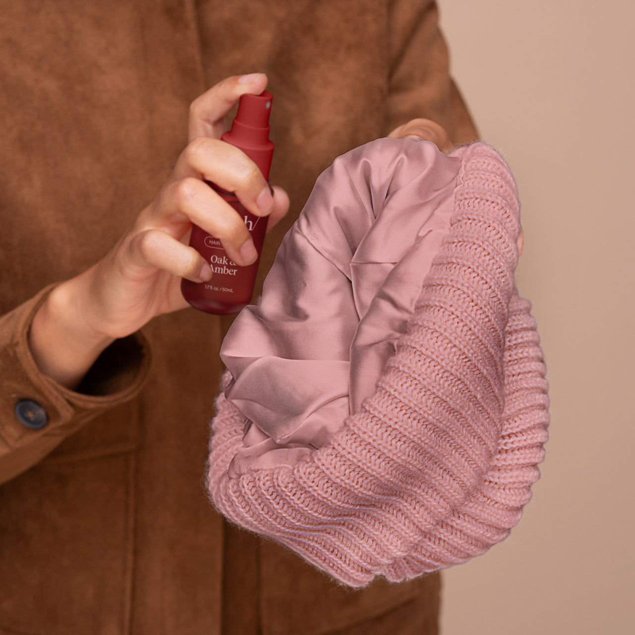 Model wearing the Kitsch Glazey Satin-Lined Beanie in blush with Kitsch Oak & Amber Hair Perfume
