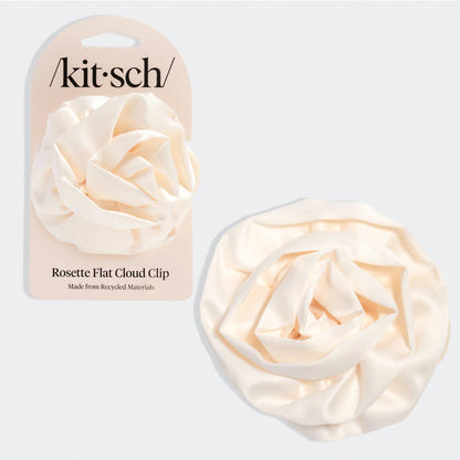 Cream-colored hair clip shaped like a soft rosette with layered, cloud-like petals. Shown next to beige packaging labeled “Kitsch” and “Rosette Flat Cloud Clip – Made from Recycled Materials.”