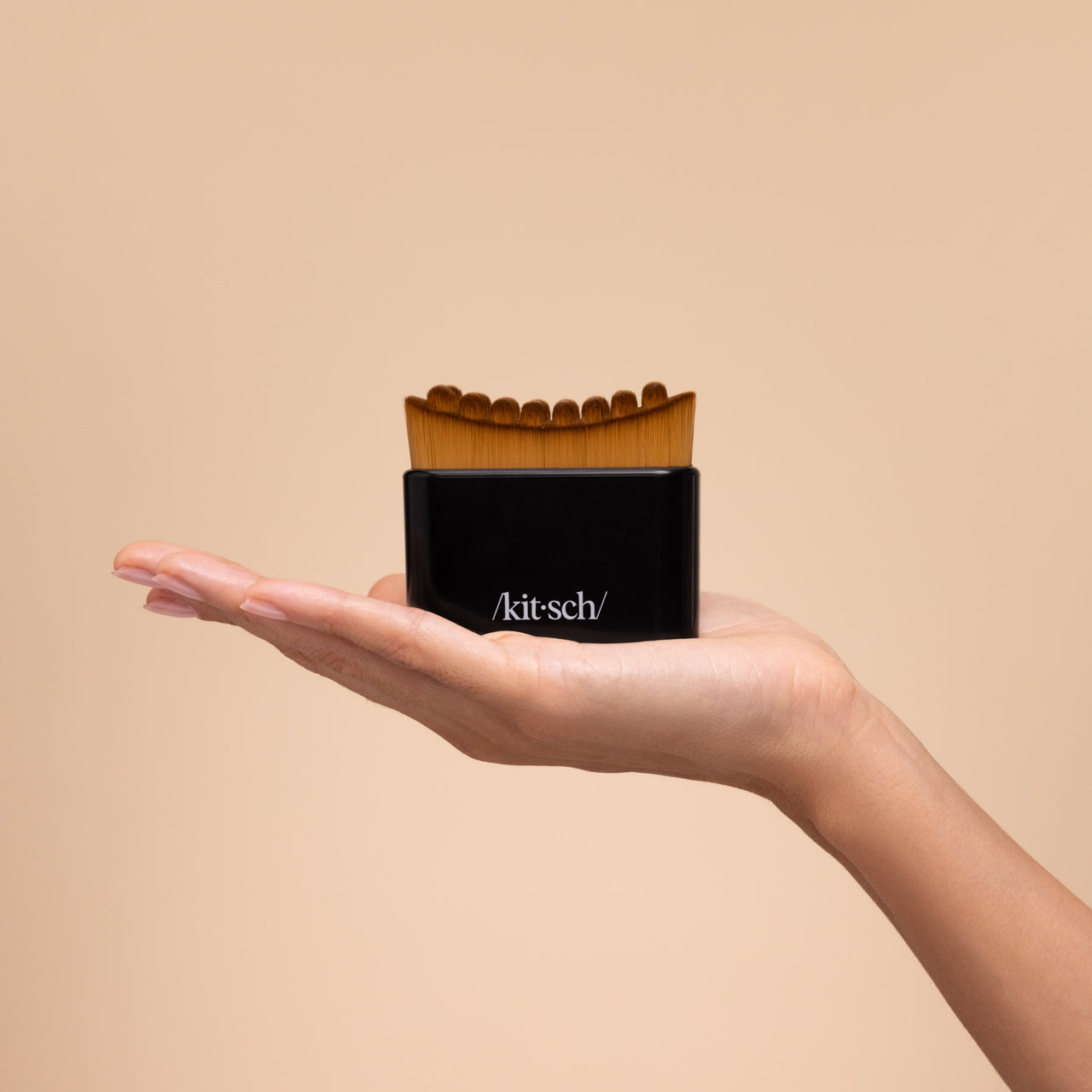 Model sweeping the black Kitsch Lymphatic Contour Face Brush upward along her jaw and neck