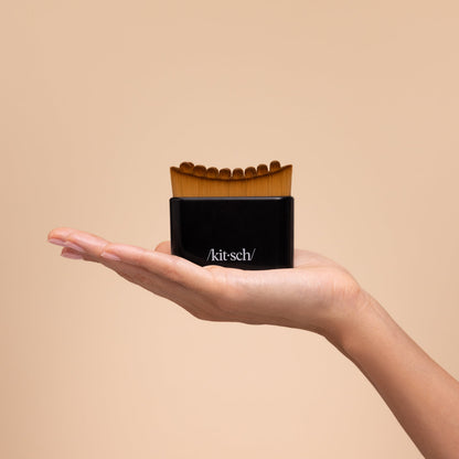 Model sweeping the black Kitsch Lymphatic Contour Face Brush upward along her jaw and neck