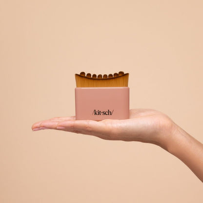 Model sweeping the terracotta Kitsch Lymphatic Contour Face Brush upward along her jaw and neck