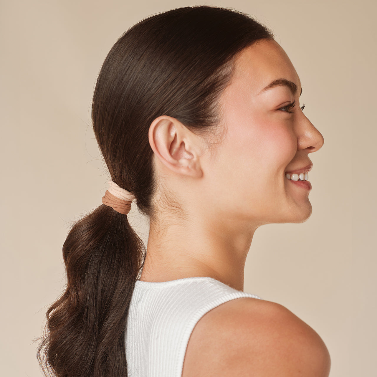 KITSCH Blush Elastic Hair Ties 20pc Set — model wearing blush hair elastic — Glide gently through hair for a tight all-day hold — consciously created from recycled materials, eco-friendly too