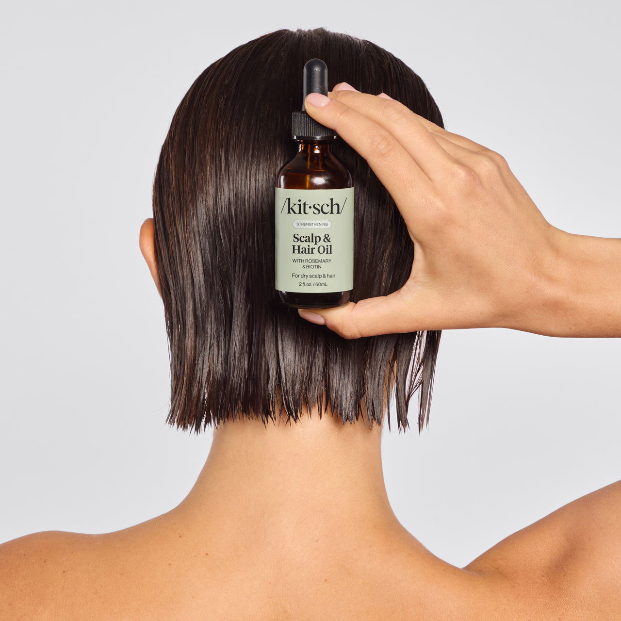 Model holding KITSCH Strengthening Rosemary & Biotin Scalp & Hair Oil bottle — 2fl oz., 100% plant-based formula with rosemary extract and biotin — free of parabens, silicones, and sulfates