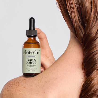KITSCH Strengthening Rosemary & Biotin Scalp & Hair Oil 2fl oz./60mL — model applying oil to scalp with precision dropper — Supports scalp health & hair strength from root to tip — lavender scent invites you to relax & indulge in an at-home spa moment