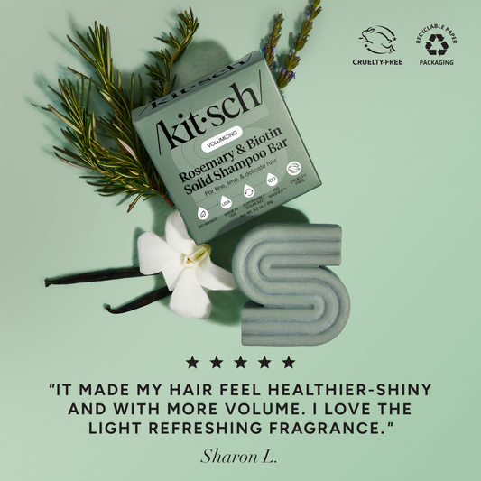 5-star customer review flat-lay for KITSCH Volumizing Rosemary & Biotin Solid Shampoo Bar on light green background styled with rosemary sprigs, white flower, and vanilla beans — Sharon L.: "IT MADE MY HAIR FEEL HEALTHIER-SHINY AND WITH MORE VOLUME. I LOVE THE LIGHT REFRESHING FRAGRANCE." — Cruelty-Free, Recyclable Paper Packaging