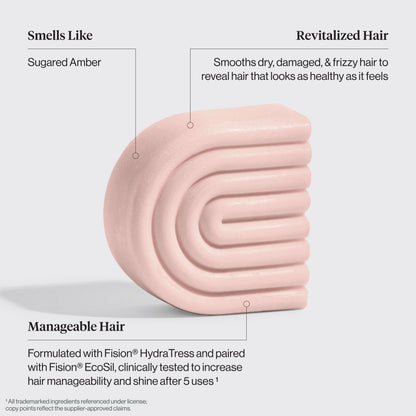 kitsch castor oil solid conditioner bar with text describing its benefits on a light gray background. Benefits are: Smells like sugared amber, revitalized hair smooths dry, damaged, and frizzy hair to reveal hair that looks as healthy as it feels, and Manageable Hair Formulated with Fision® HydraTress and paired with Fision® EcoSil, clinically tested to increase hair manageability and shine after 5 uses