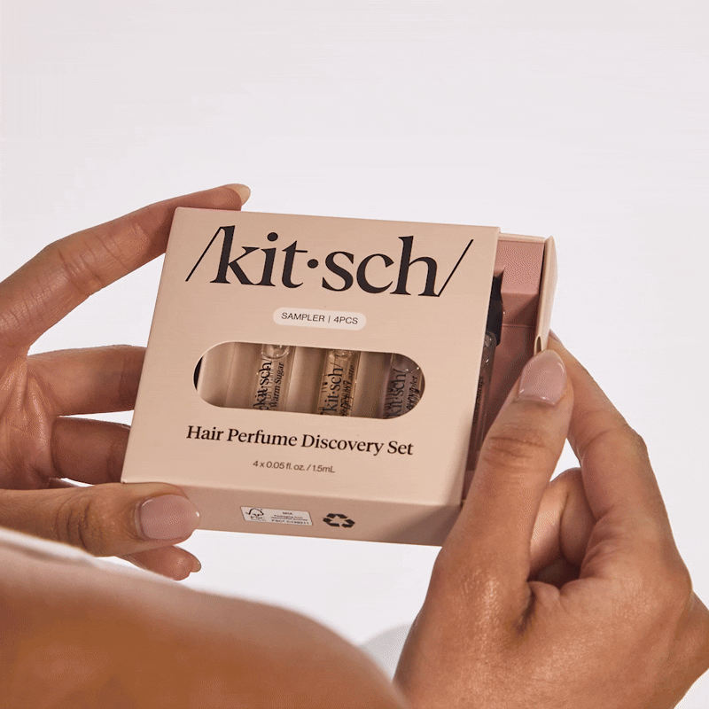 Model holding Kitsch Hair Perfume Discovery Set mini fragrance in hand against a warm background