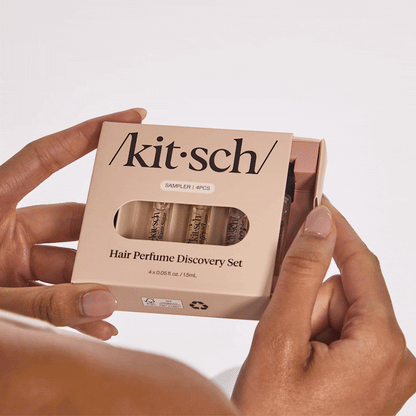 Model holding Kitsch Hair Perfume Discovery Set mini fragrance in hand against a warm background
