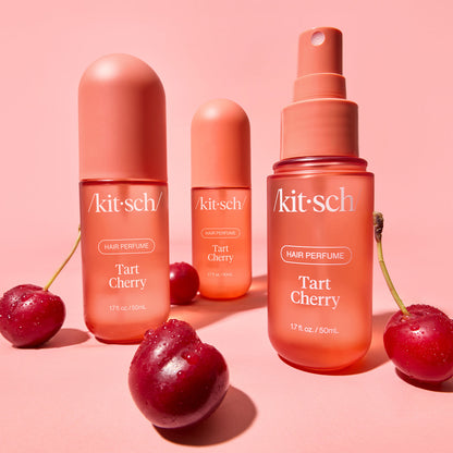 Kitsch Tart Cherry Hair Perfume bottle held by a hand against a warm neutral background