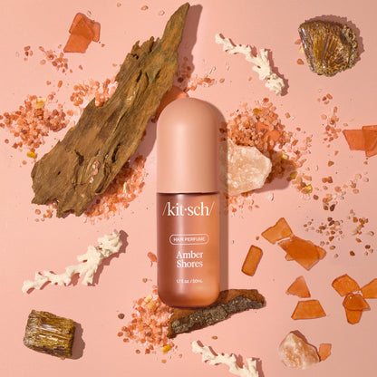 Model misting Kitsch Amber Shores Hair Perfume onto long, wavy hair