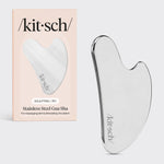 Kitsch Stainless Steel Gua Sha tool lying flat on marble surface showing curved edges