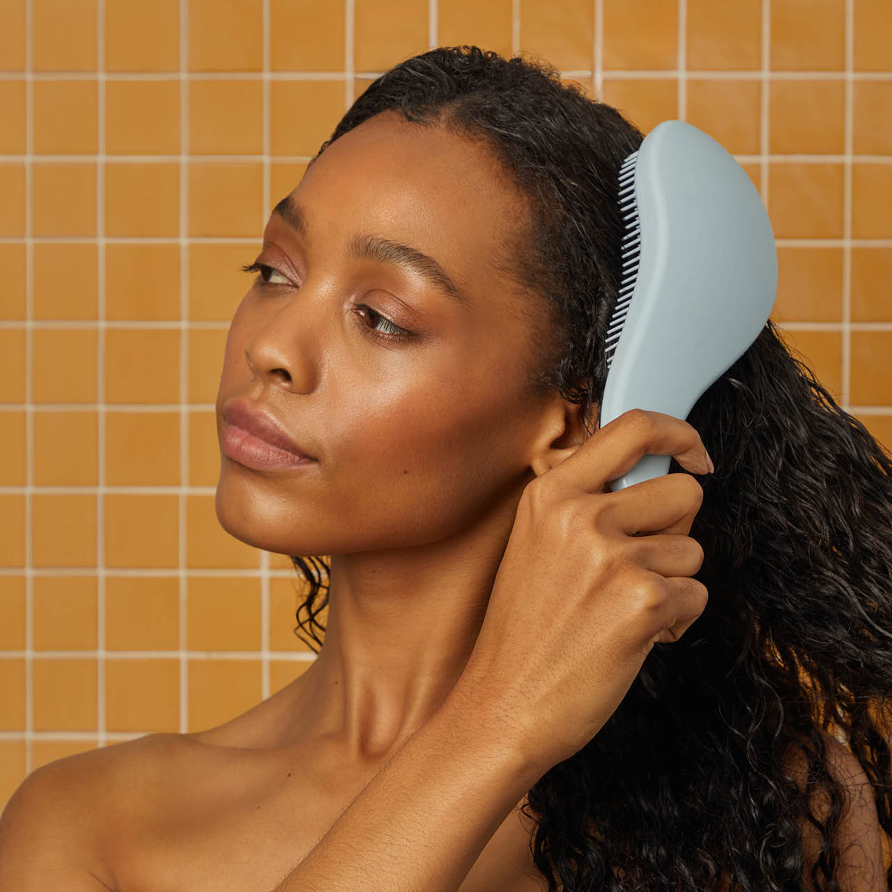 Model using the Kitsch Haze Blue Detangling Brush to detangle hair